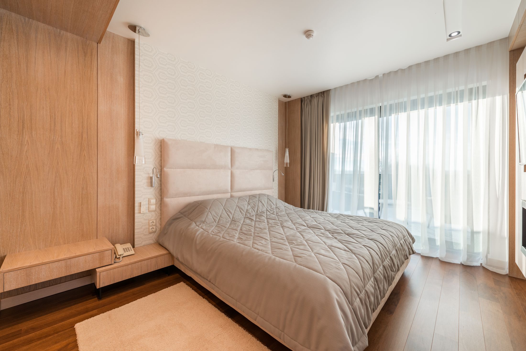 A bright furnished bedroom with a comfortable bed and warm natural light